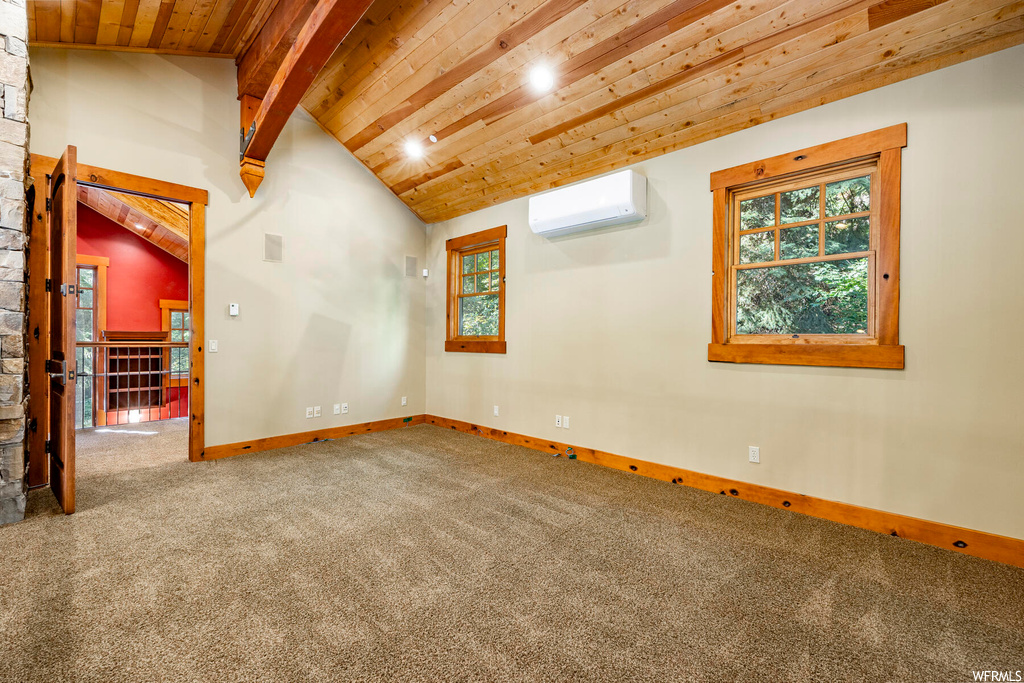 Carpeted empty room featuring a wall mounted air conditioner, lofted ceiling with beams, and wooden ceiling