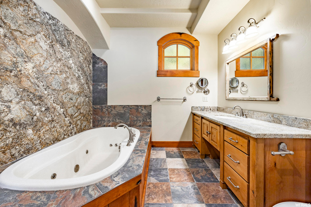 Bathroom featuring vanity, a bathtub, a textured ceiling, tile flooring, and mirror