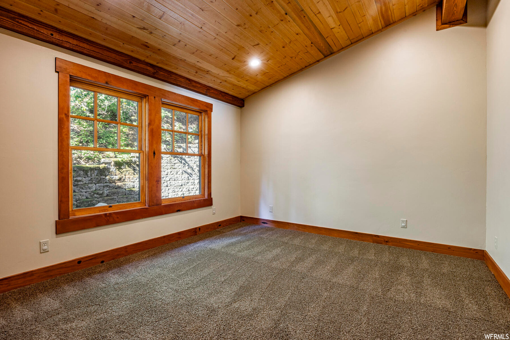 Unfurnished room featuring light carpet, wooden ceiling, and vaulted ceiling