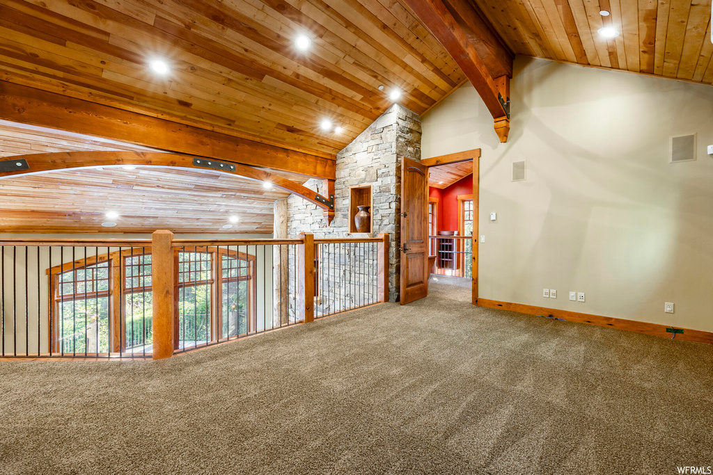 Carpeted empty room with wood ceiling and lofted ceiling with beams
