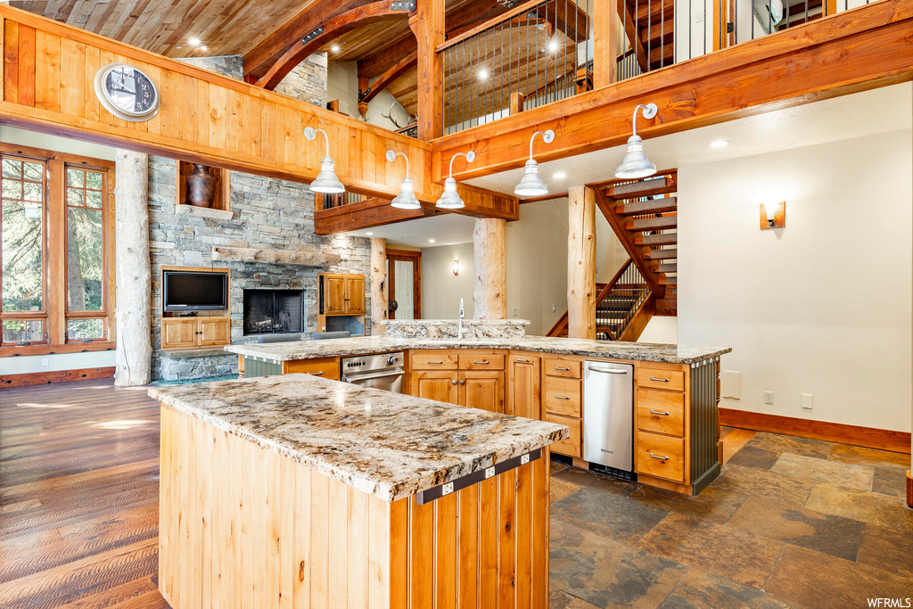 Kitchen featuring dark hardwood floors, light stone countertops, wood ceiling, brown cabinets, hanging light fixtures, lofted ceiling with beams, and a high ceiling