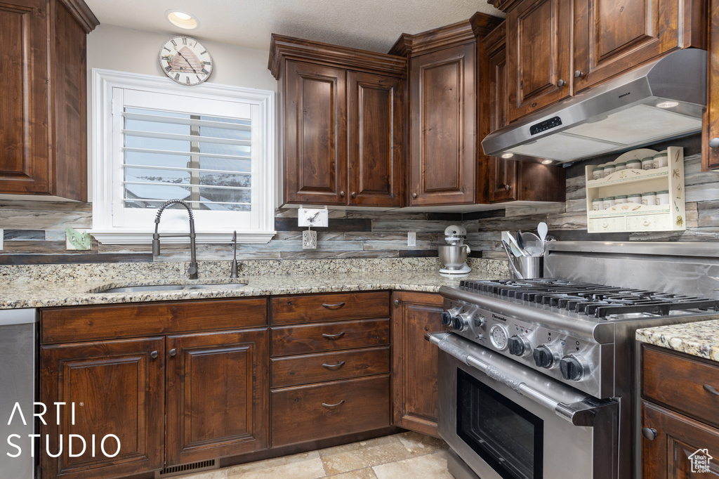 Kitchen featuring sink, light stone counters, appliances with stainless steel finishes, and backsplash
