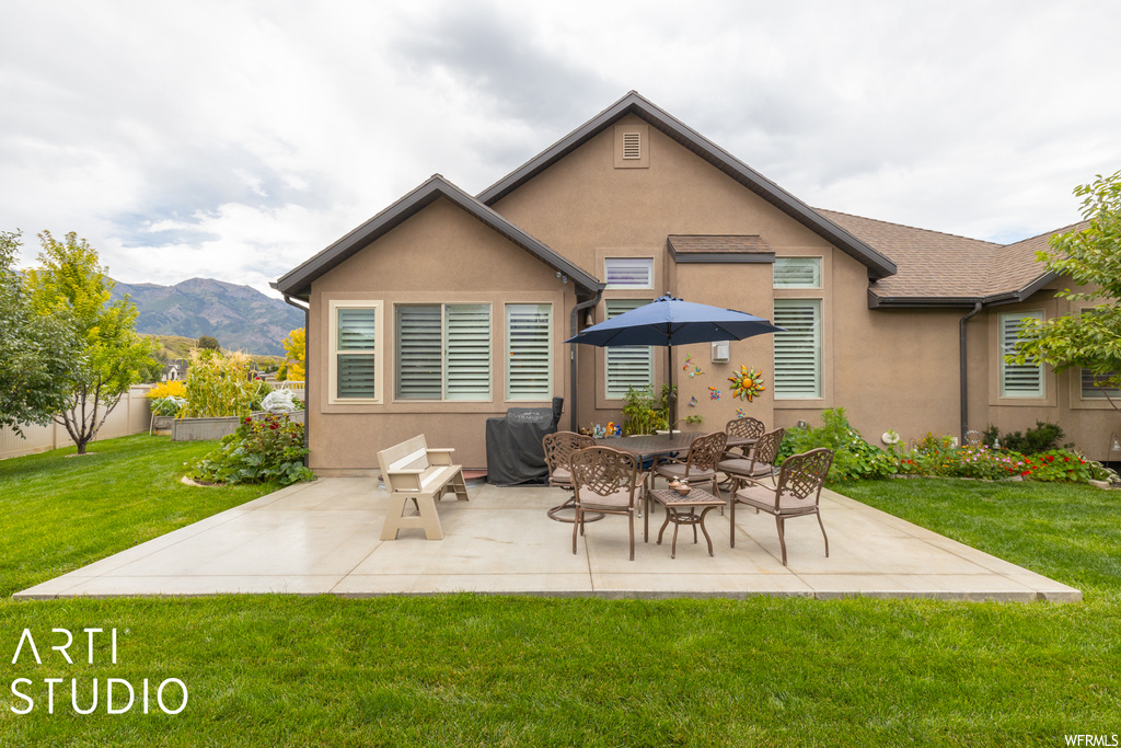 Back of property with a lawn, a patio area, and a mountain view
