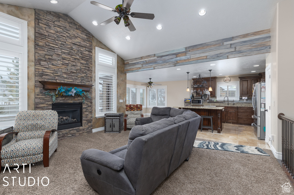 Living room featuring a fireplace, light tile floors, ceiling fan, sink, and vaulted ceiling