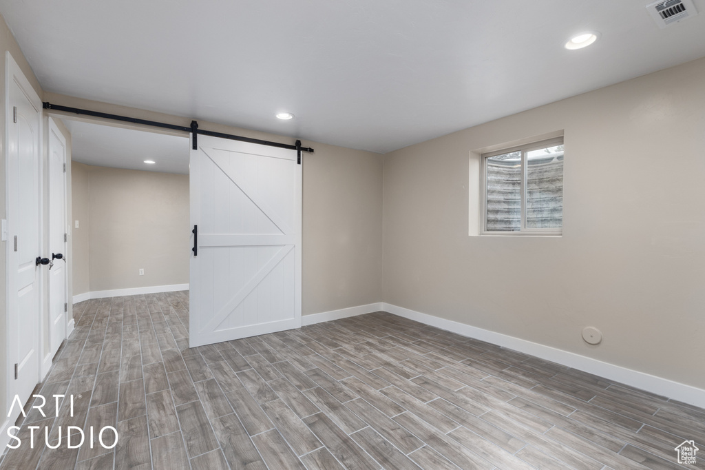 Unfurnished room with a barn door and light wood-type flooring