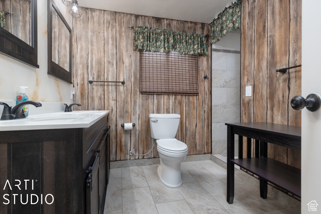 Bathroom with tile floors, vanity, toilet, and wood walls