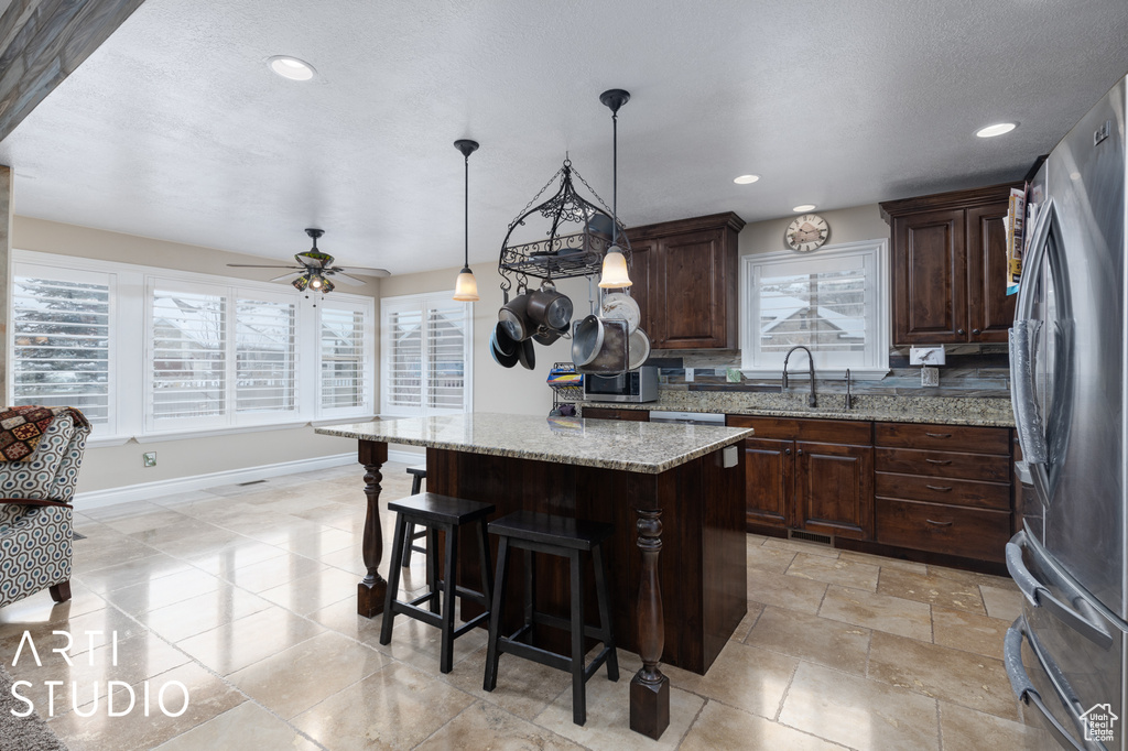 Kitchen with hanging light fixtures, appliances with stainless steel finishes, a center island, ceiling fan, and sink