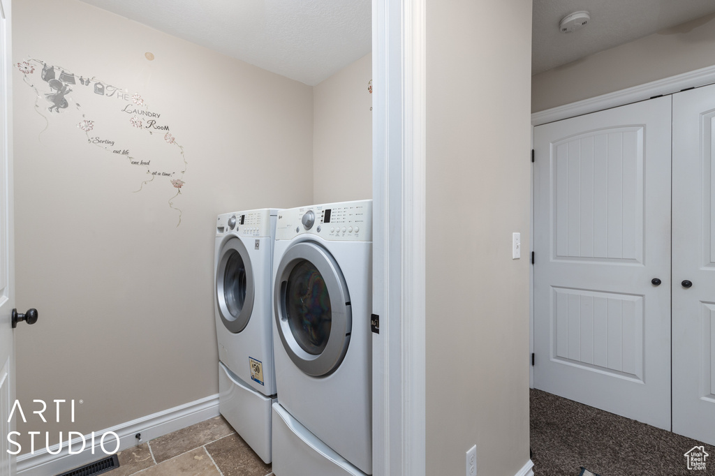 Laundry area with dark tile floors and washing machine and dryer