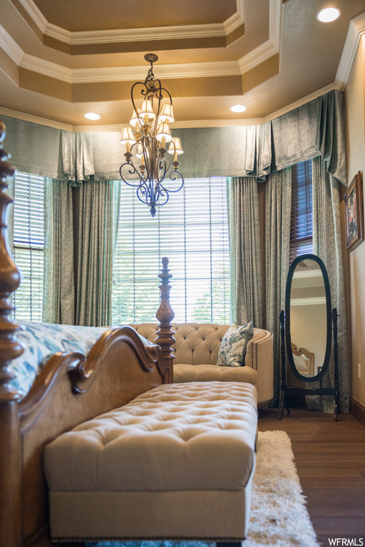 Bedroom featuring a chandelier, ornamental molding, a tray ceiling, and light hardwood flooring