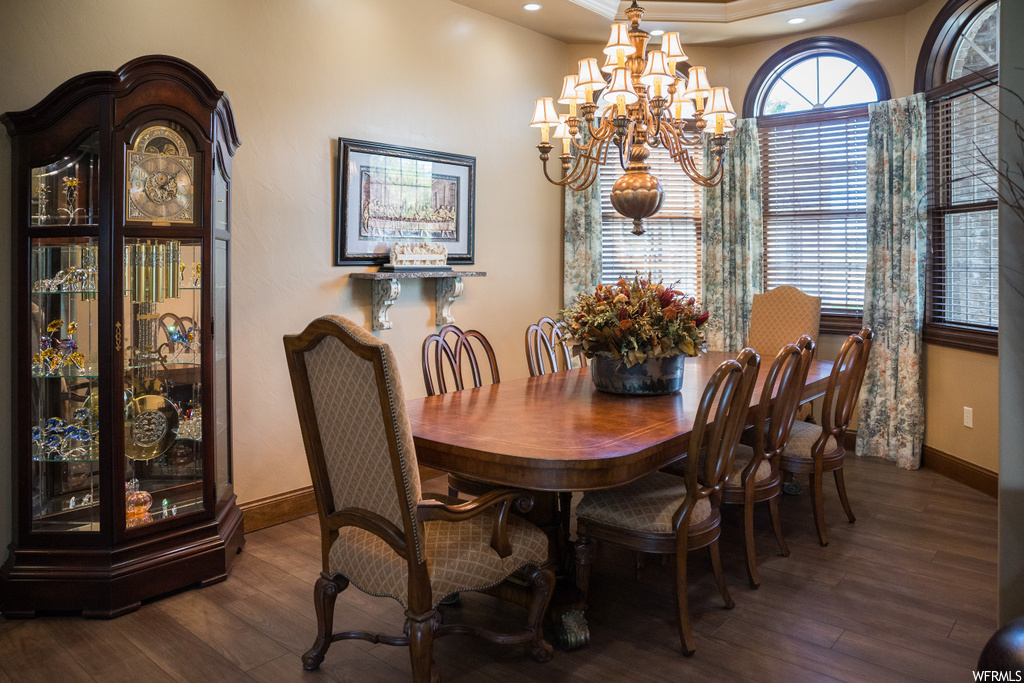 Hardwood floored dining space with a chandelier and a raised ceiling