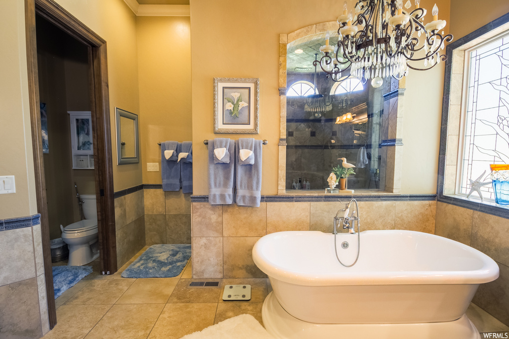 Bathroom featuring a bathing tub, light tile flooring, and tile walls