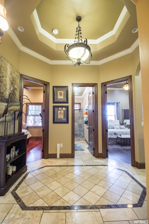 Foyer featuring crown molding, a tray ceiling, and light tile floors