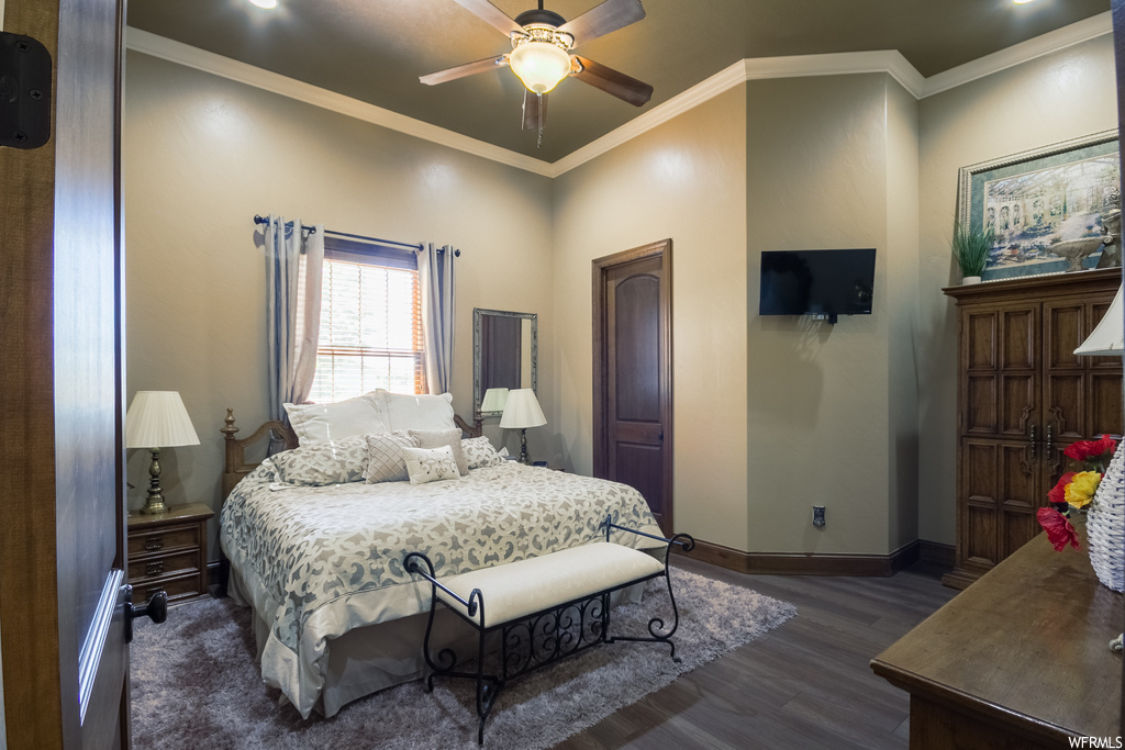 Hardwood floored bedroom featuring ornamental molding and ceiling fan