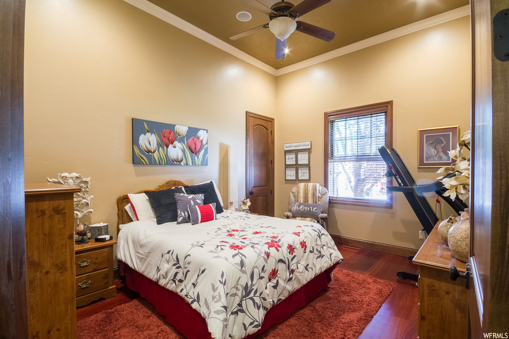 Bedroom with ornamental molding, ceiling fan, and dark hardwood flooring