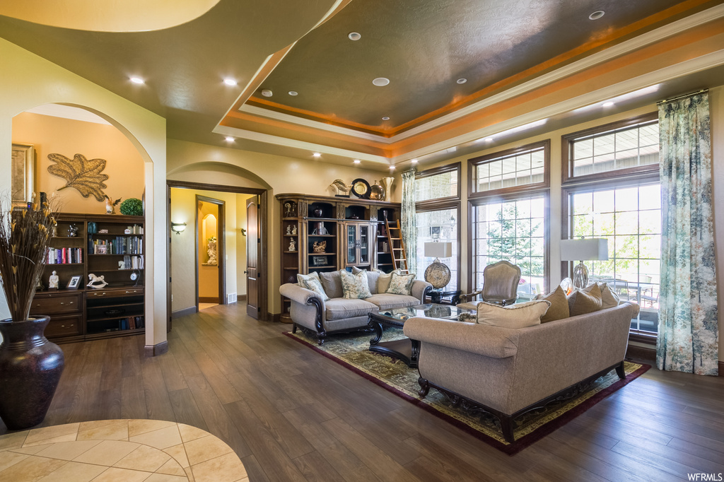 Living room with dark hardwood floors, crown molding, and a raised ceiling