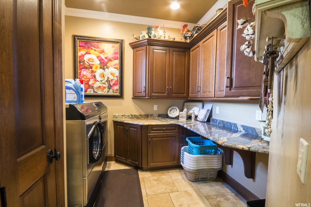 Laundry area featuring ornamental molding, washing machine and clothes dryer, and light tile flooring