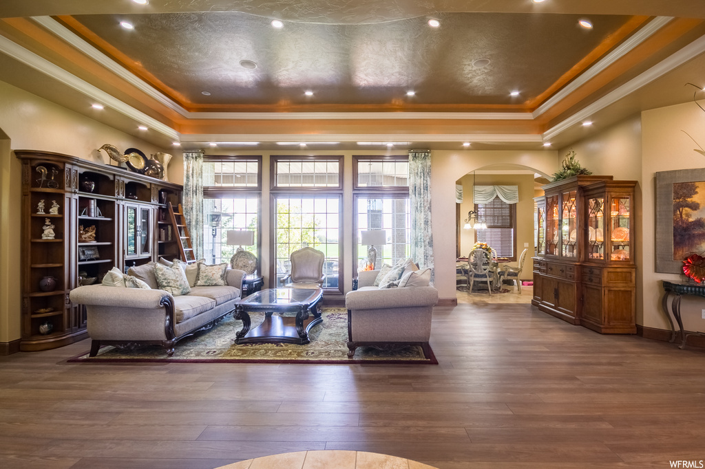 Living room with crown molding, a tray ceiling, and light hardwood floors