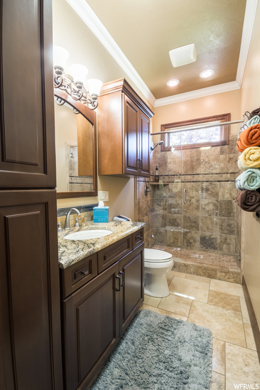 Bathroom featuring ornamental molding, mirror, light tile floors, oversized vanity, and an enclosed shower