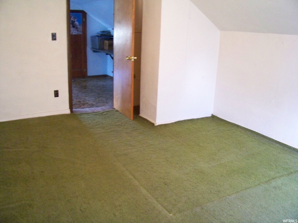 Carpeted spare room with vaulted ceiling