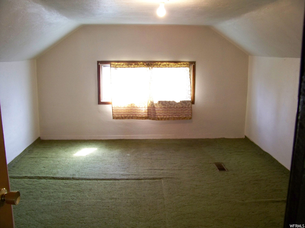 Additional living space featuring a textured ceiling, light carpet, and lofted ceiling