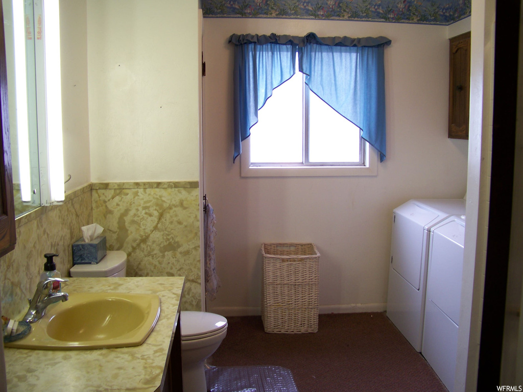 Bathroom with vanity, mirror, and washer and dryer
