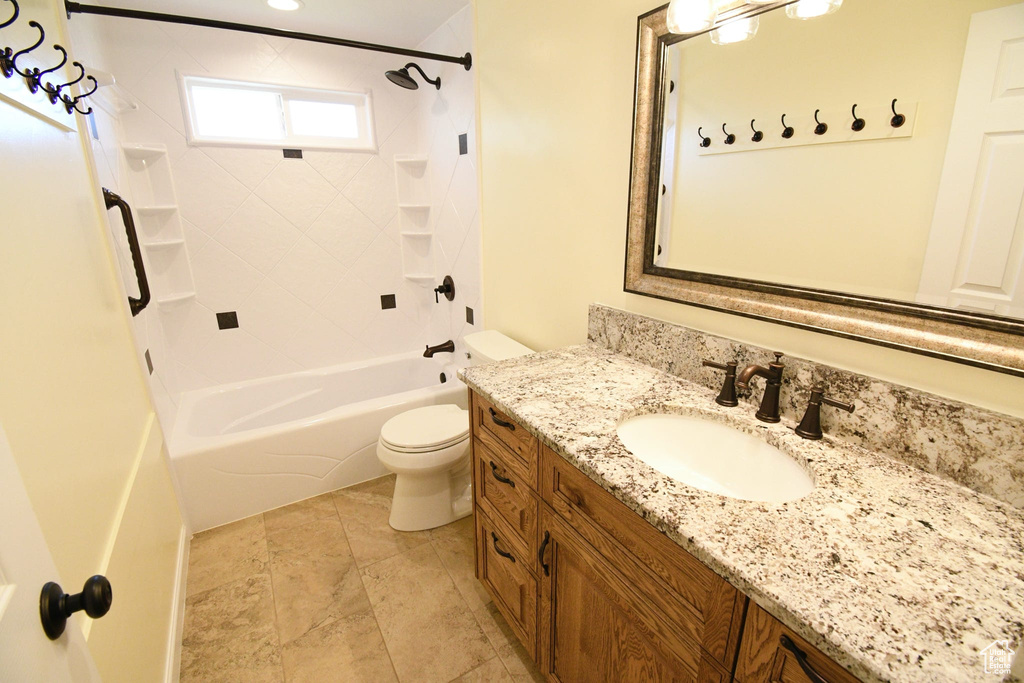 Full bathroom featuring vanity with extensive cabinet space, toilet, tiled shower / bath, and tile flooring