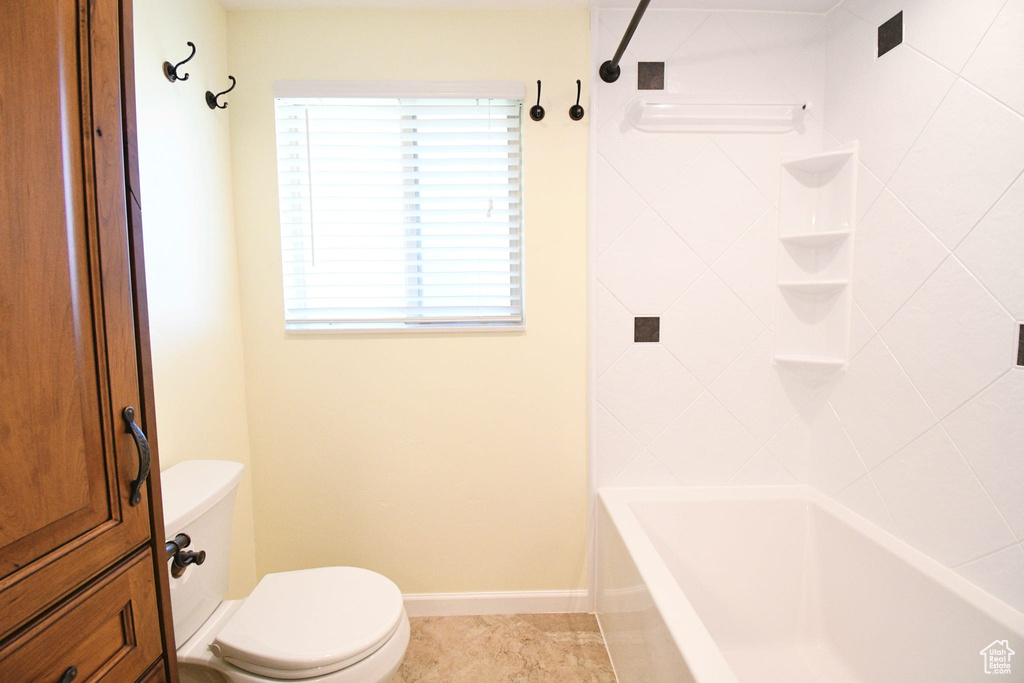 Bathroom featuring tile floors, toilet, and tiled shower / bath
