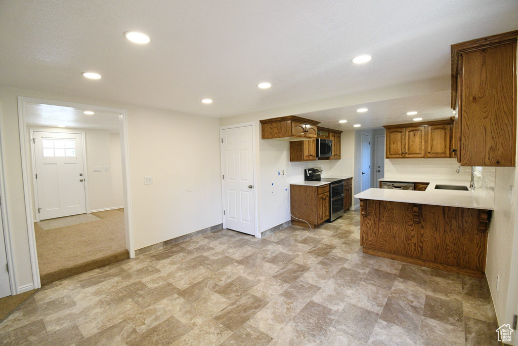 Kitchen with kitchen peninsula, light tile floors, appliances with stainless steel finishes, and sink