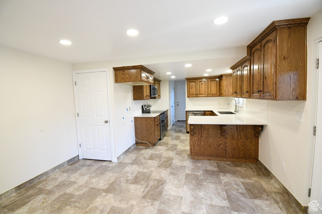 Kitchen with light tile floors, appliances with stainless steel finishes, kitchen peninsula, and sink