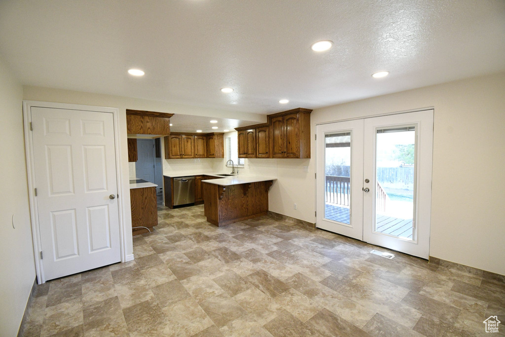 Kitchen featuring french doors, kitchen peninsula, sink, light tile floors, and dishwasher