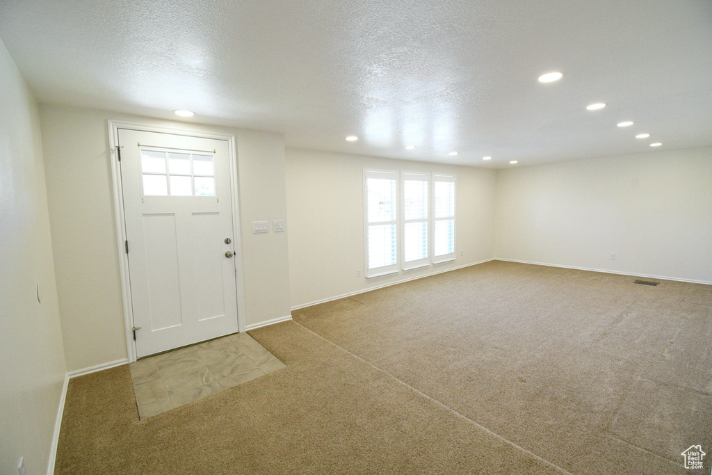 Carpeted entryway featuring a wealth of natural light and a textured ceiling
