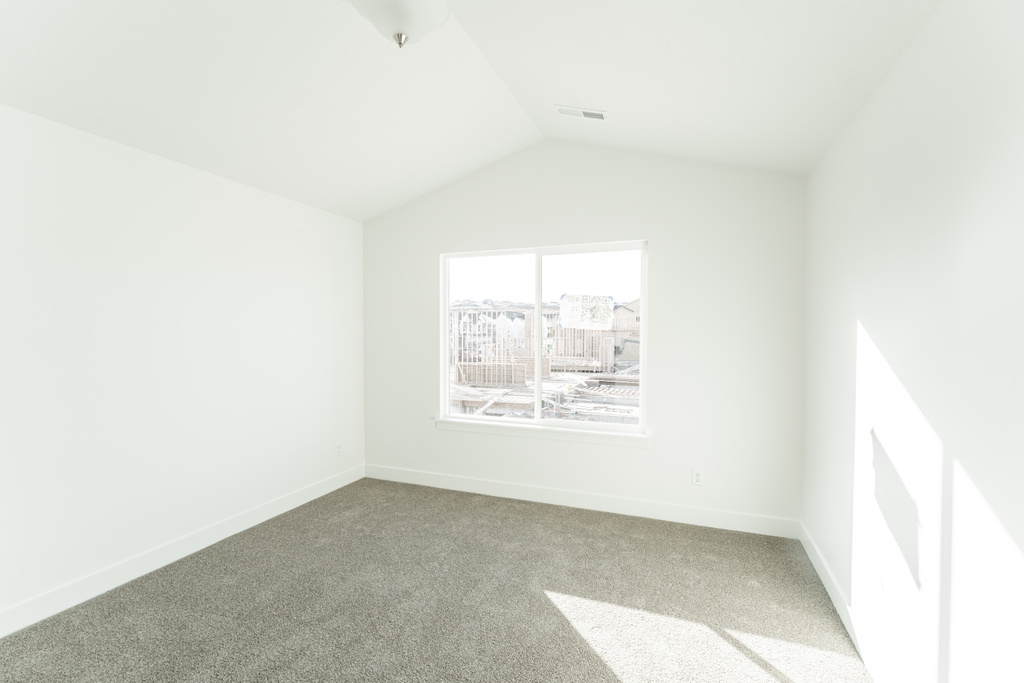 Spare room with vaulted ceiling and light colored carpet