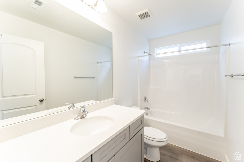 Full bathroom with large vanity, hardwood / wood-style flooring, bathtub / shower combination, and toilet