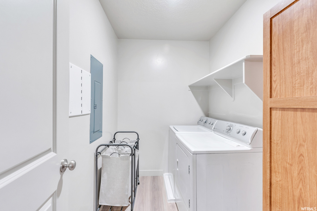 Laundry area with washer and clothes dryer and light hardwood flooring