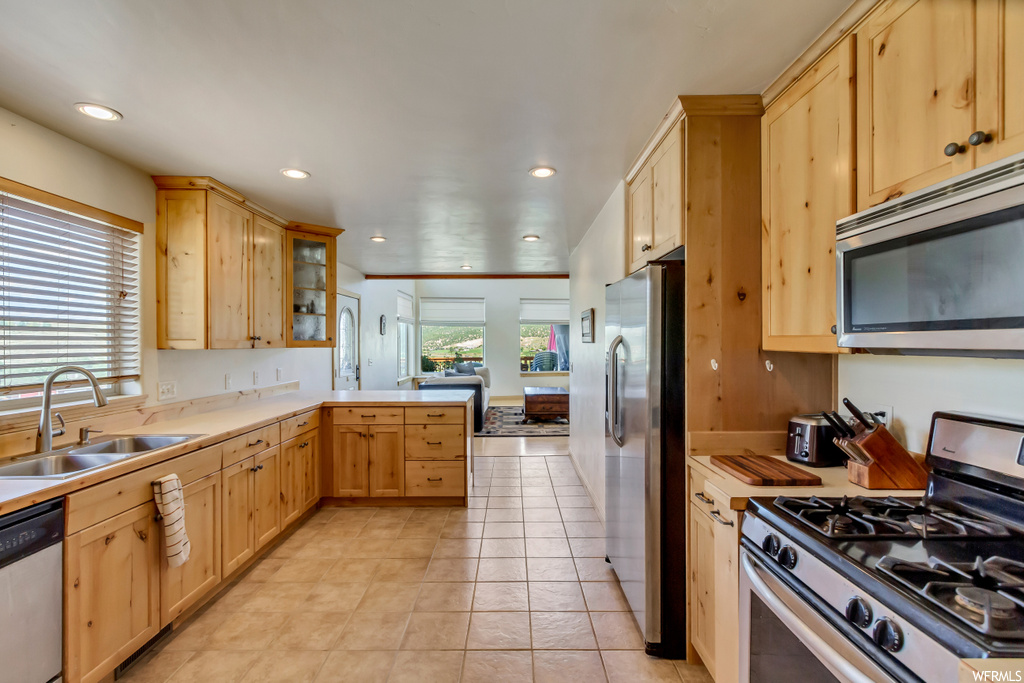Kitchen featuring light tile flooring, brown cabinets, light countertops, and stainless steel appliances