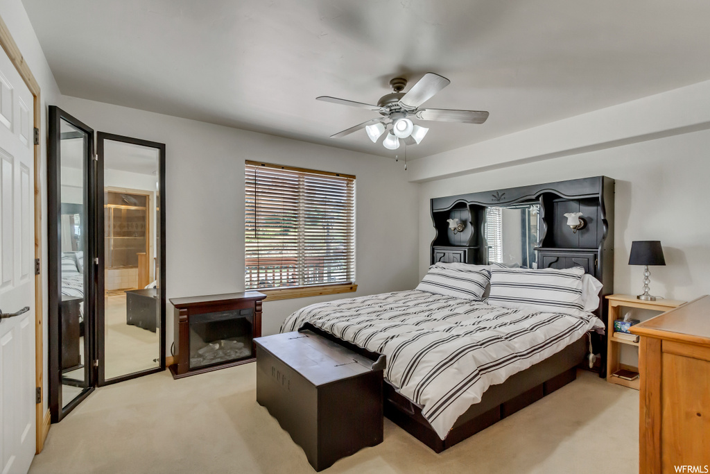 Carpeted bedroom with stacked washer / dryer and ceiling fan