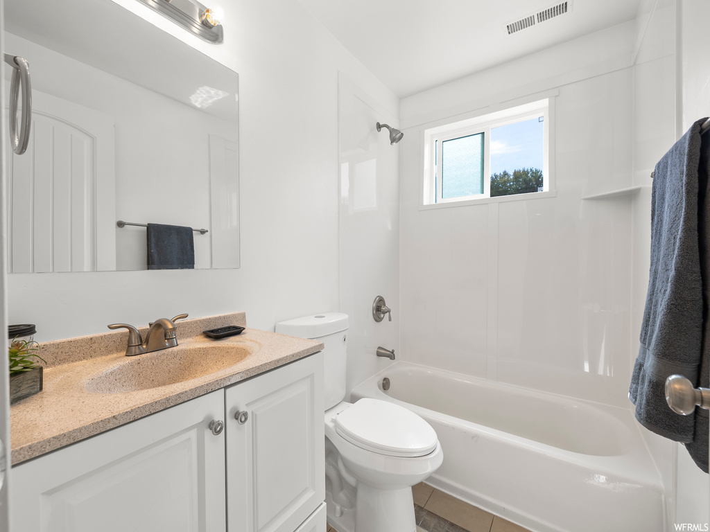 Full bathroom featuring washtub / shower combination, mirror, light tile floors, and vanity