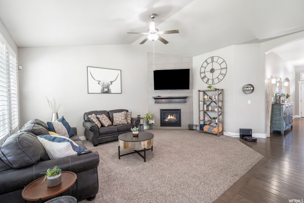 Living room featuring a fireplace, vaulted ceiling, hardwood floors, and ceiling fan