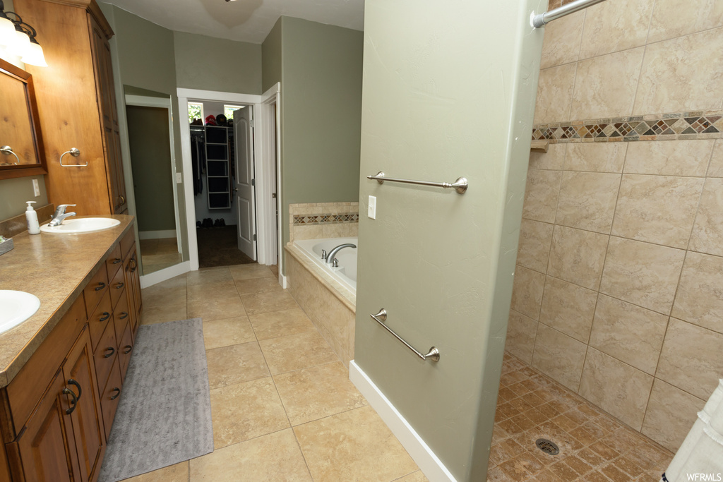 Bathroom featuring shower with separate bathtub, mirror, light tile floors, and dual bowl vanity