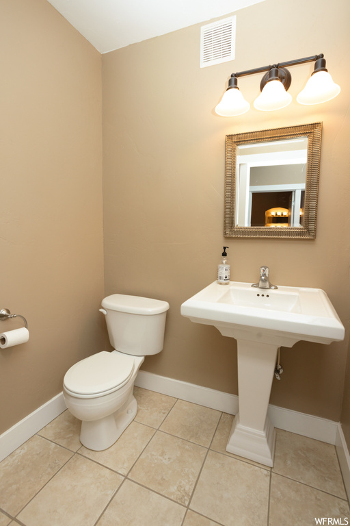 Bathroom featuring washbasin, mirror, and light tile floors