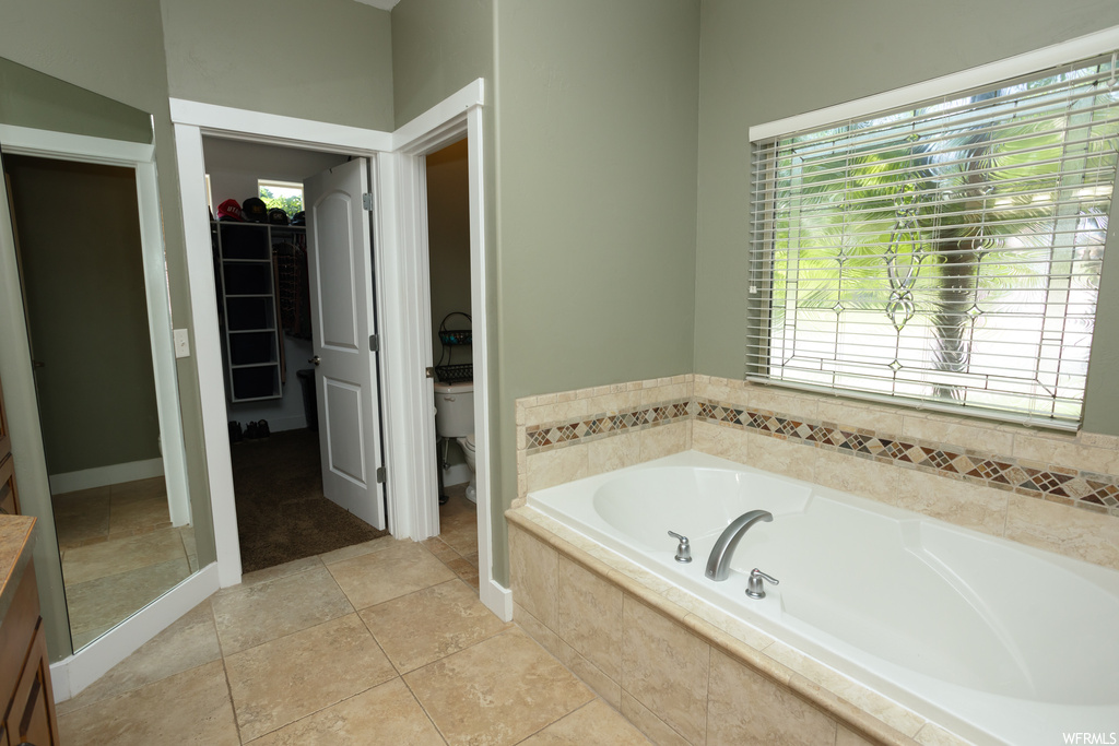 Bathroom with tiled tub and light tile flooring