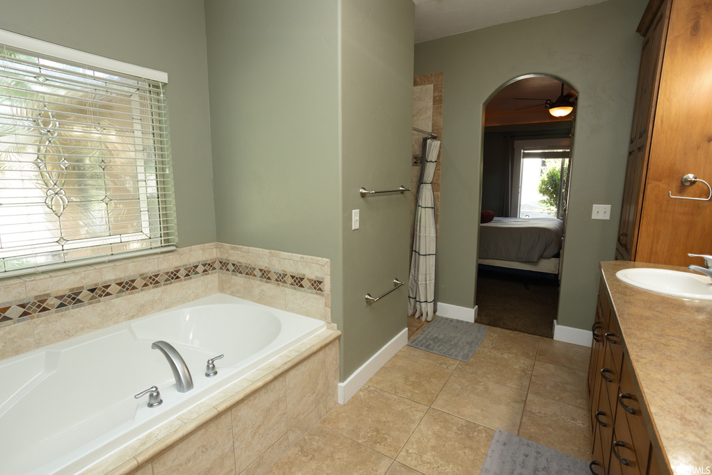 Bathroom featuring vanity, light tile flooring, and tiled bath