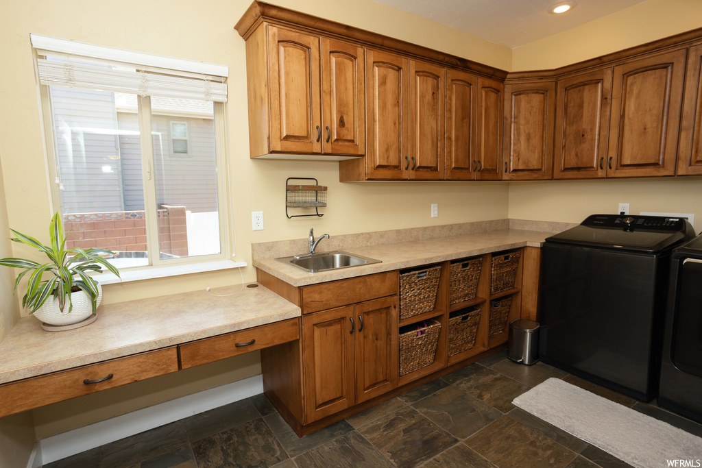 Kitchen with light countertops, dark tile flooring, washer and clothes dryer, and brown cabinets