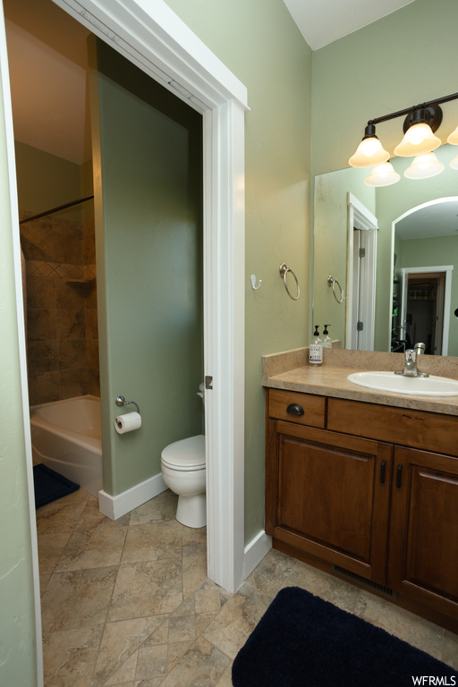 Full bathroom with vanity with extensive cabinet space, tiled shower / bath combo, mirror, and light tile floors