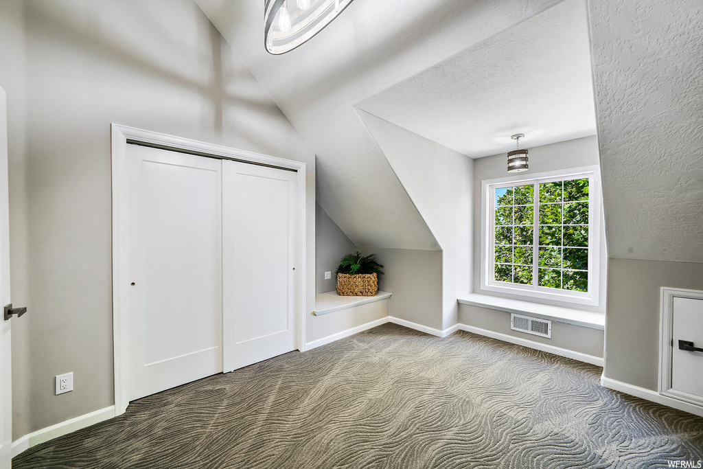Additional living space featuring light carpet, lofted ceiling, and a textured ceiling