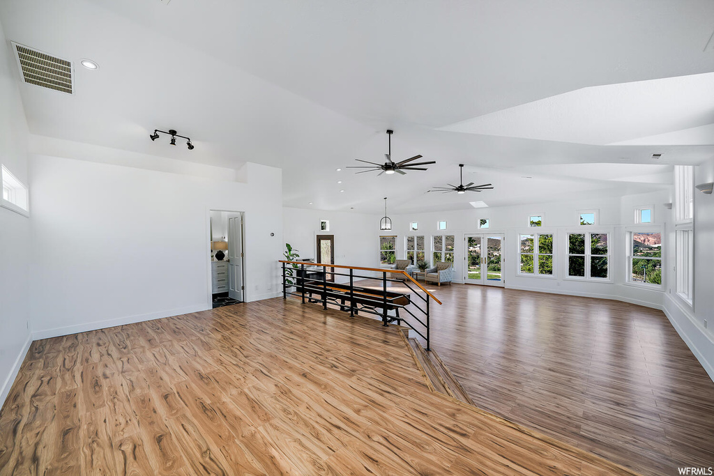 Interior space with track lighting, vaulted ceiling, light hardwood floors, and ceiling fan