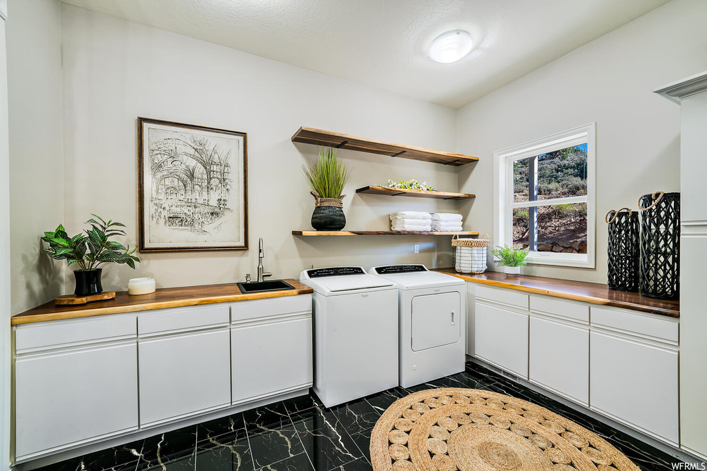 Kitchen featuring independent washer and dryer, dark tile flooring, light countertops, and white cabinetry