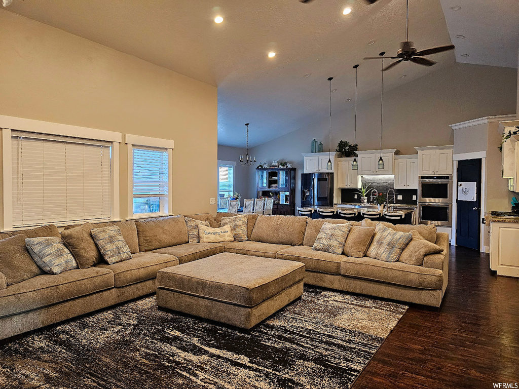 Living room featuring dark hardwood floors, vaulted ceiling, a high ceiling, and ceiling fan