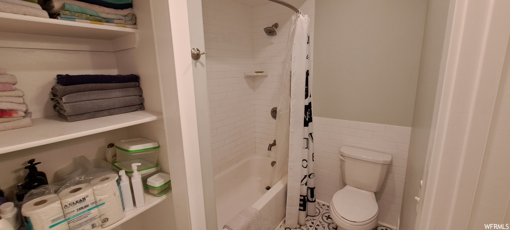 Bathroom with tile walls and shower / tub combo with curtain