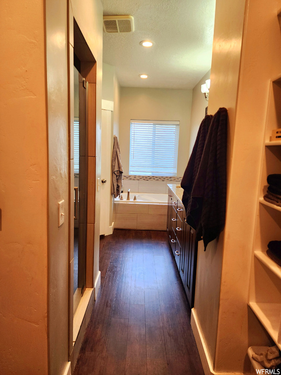 Bathroom featuring a tub, vanity, a textured ceiling, and dark hardwood floors